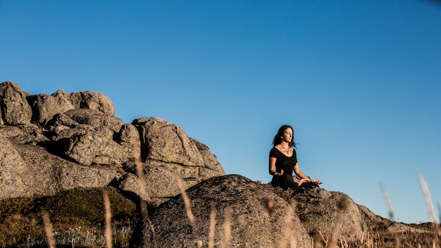 Yoga instructor Lara Zilibowitz sitting in lotus pose in the outdoors.