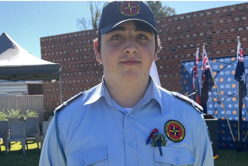 Cadet Unit Leader Sebastian Ruddock stands in front of the ceremony podium at Austrlian nationsal flag dressed in parade uniform