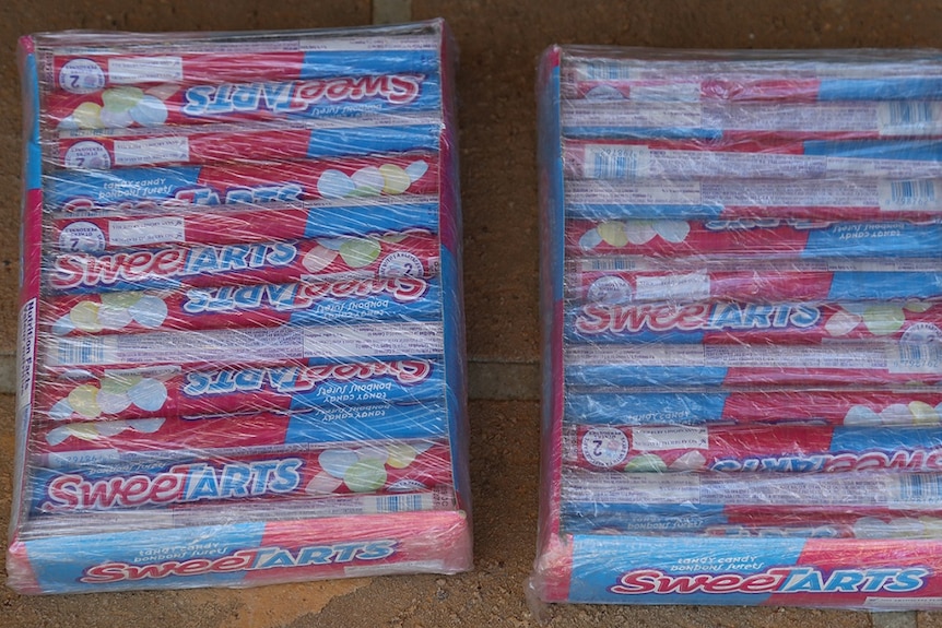 Two large boxes containing packets of red and blue candy.