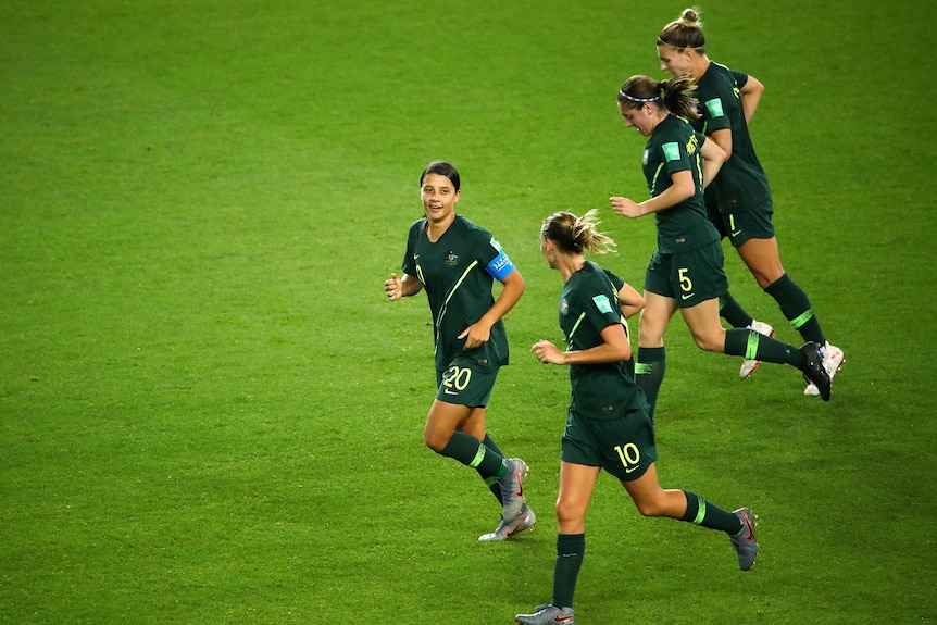 Four Matildas players job on green grass