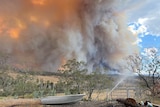 A large plume of smoke and fire over a country landscape.