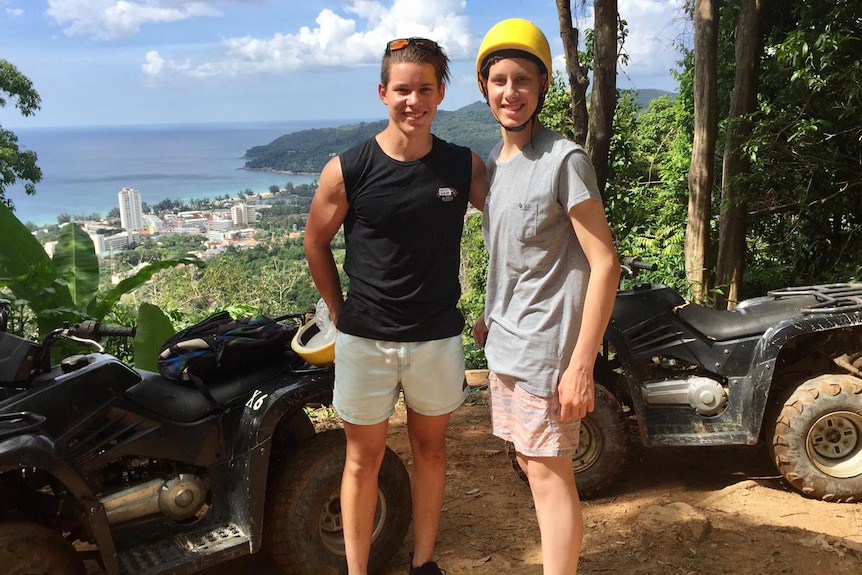 Two young men on holiday with a coastline in the background.