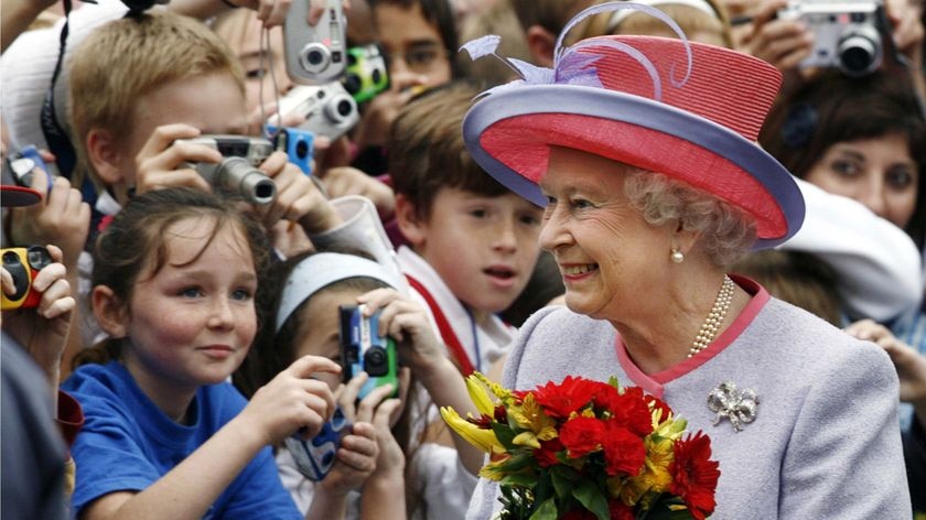 Queen Elizabeth II carries flowers given to her by schoolchildren.