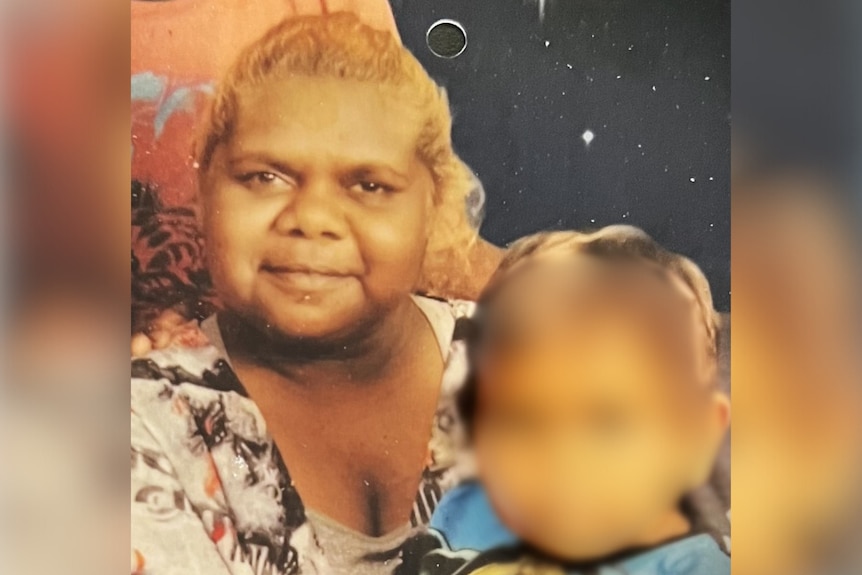 A printed out photo of a young Aboriginal woman with a young boy, whose face is blurred out.