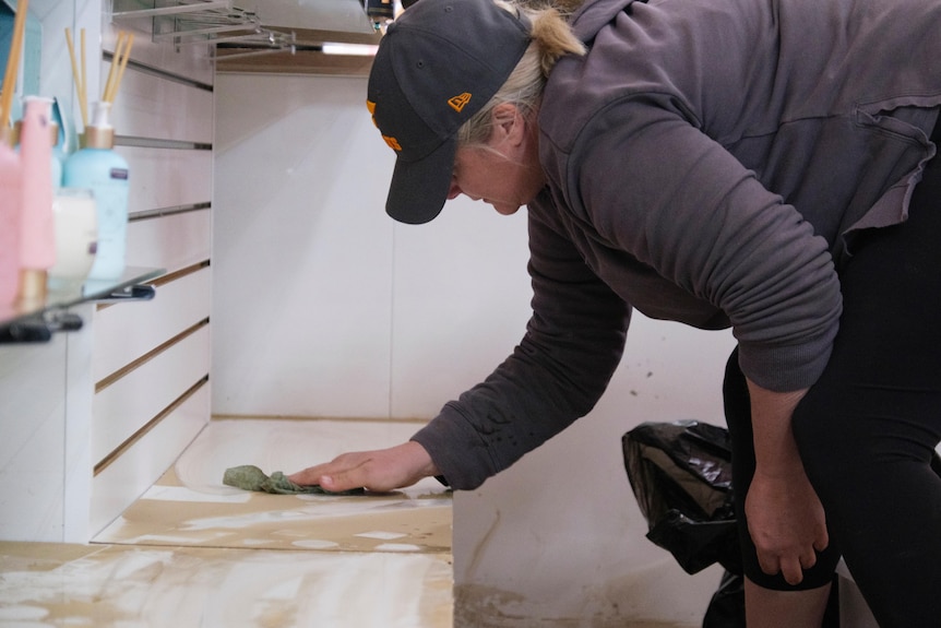 A woman wipes down a dirty counter in a store