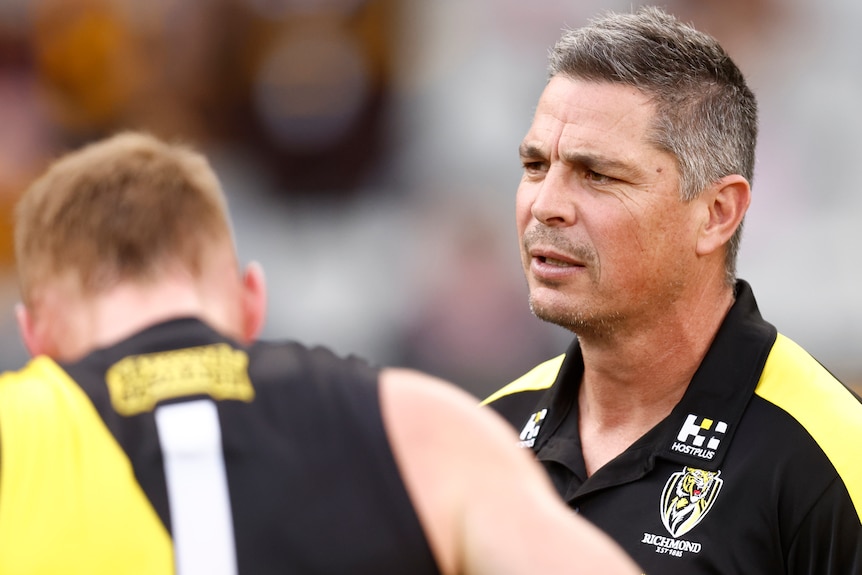 Adam Kingsley speaks to Richmond players while wearing a Richmond polo