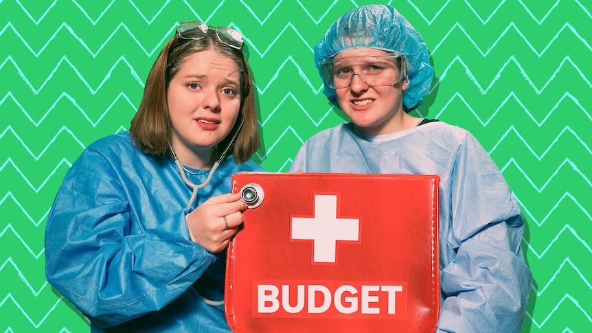 Two girls dressed in surgical equipment hold a medical case with 'Budget' printed on it.