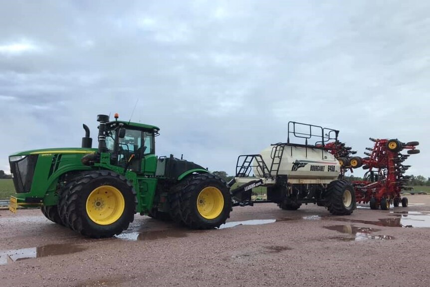 A large tractor is parked up surrounded by puddles