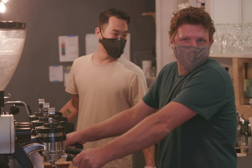 Nick Sharp wearing green t-shirt and protective face mask, at the espresso machine in his Miami cafe