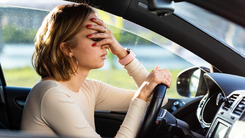 A woman looking tired and stressed while sitting in traffic.