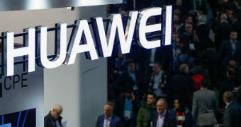 A neon logo of Huawei suspended above a passing crowd