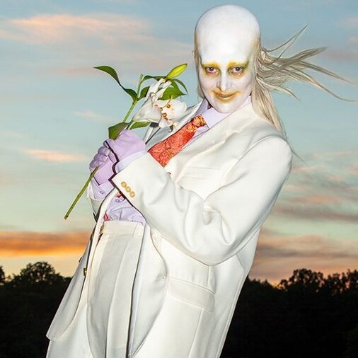 Fever Ray holds flowers in a white suit