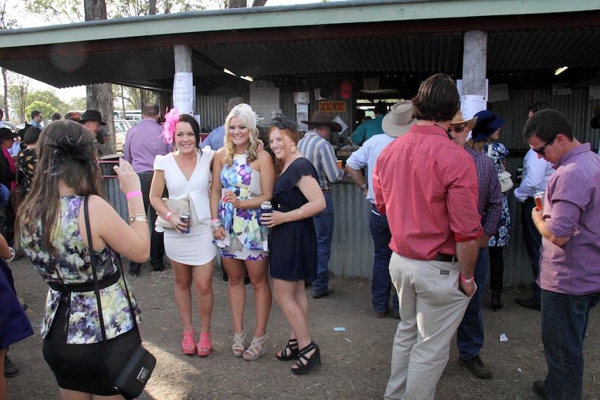 Girls have photo taken in front of bar at the Burrandowan Picnic Races.