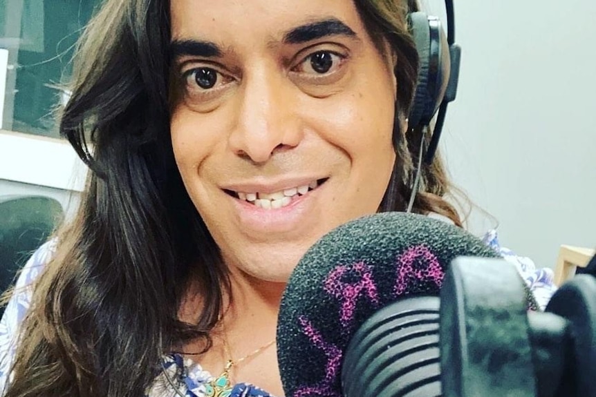 A close up of a woman smiling in front of a microphone, wears headset. 