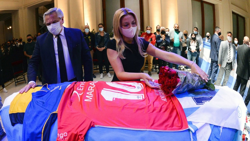 Argentina President Alberto Fernandez and first lady Fabiola Yañez stand over Diego Maradona