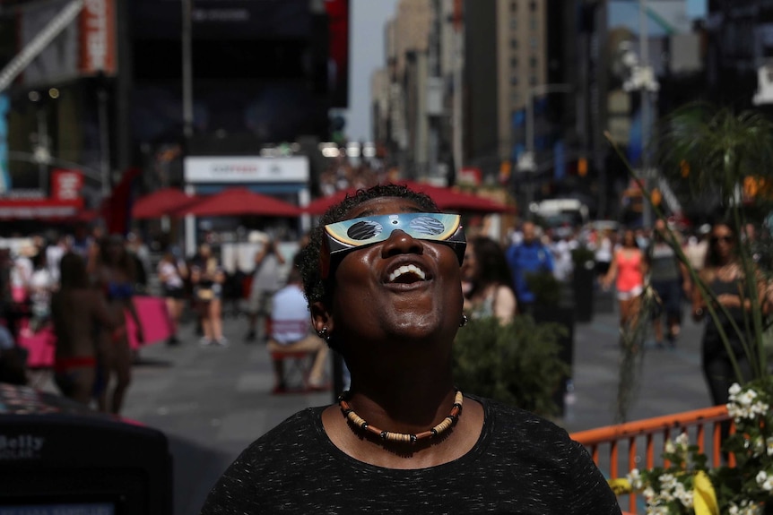 A woman views the solar eclipse at Times Square in Manhattan, New York
