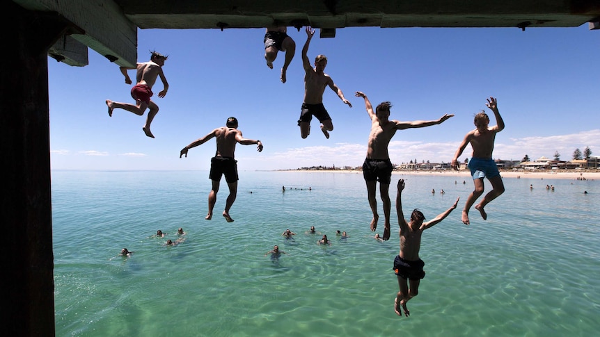 Jetty jumpers escape the heat by cooling off at Henley Beach