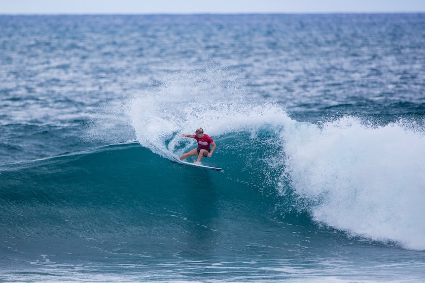 Woman in red surfing large wave