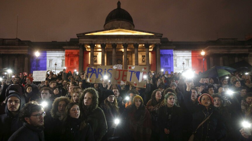 people hold candles and lights at Trafalgar Square in London