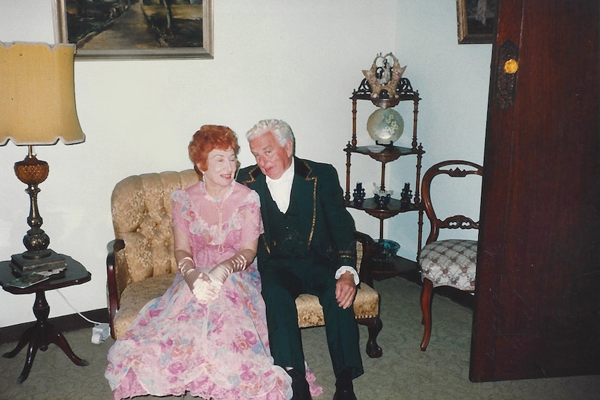 A woman and a man in formal clothes pictured at home