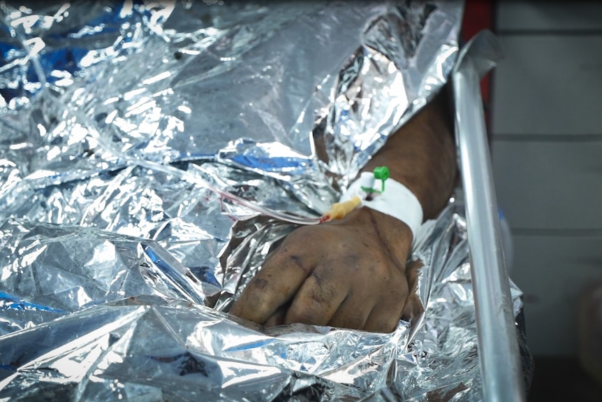 A child's hand on a silver space blanket 