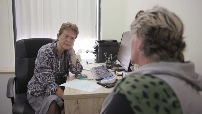 Dr Kate Shapland sitting at her desk in her surgery consulting with an unidentified patient