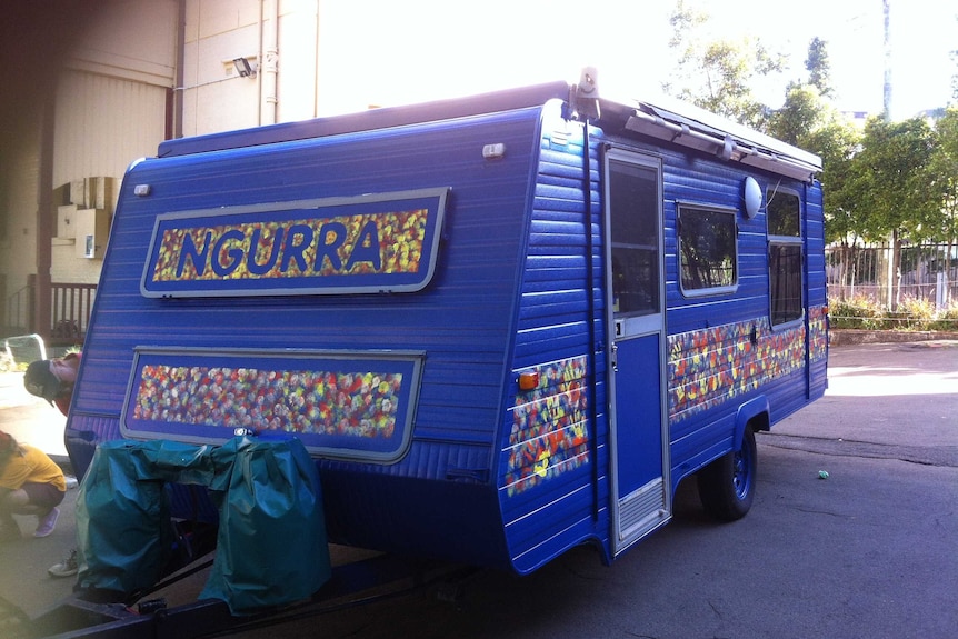 A purple therapy van is parked outside with a multicoloured stripe on the bottom right side.