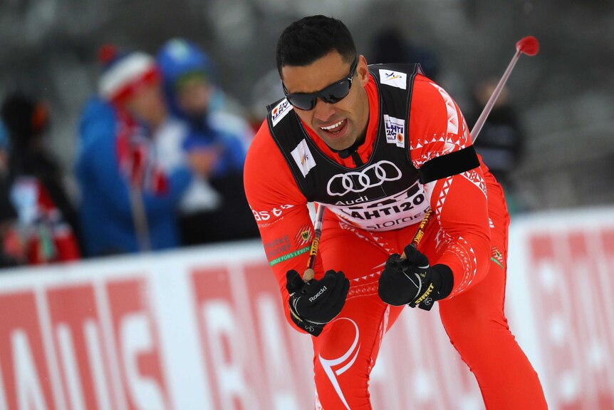 Pita Taufatofua tucks ski poles under his arms as he skis.