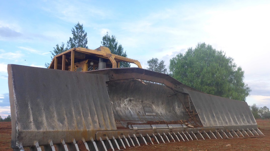 Front blade of a bulldozer the size of a house stands idle as farmers in western New South Wales opt not to clear land