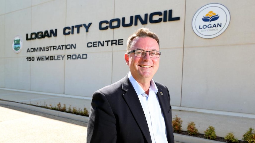 Then-Logan City Council mayor Luke Smith standing outside a building with the sign, Logan City Council Administration Centre.