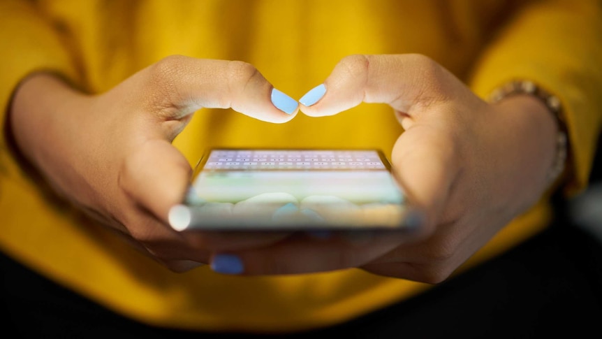 Close up of a woman's hands typing on a smartphone.