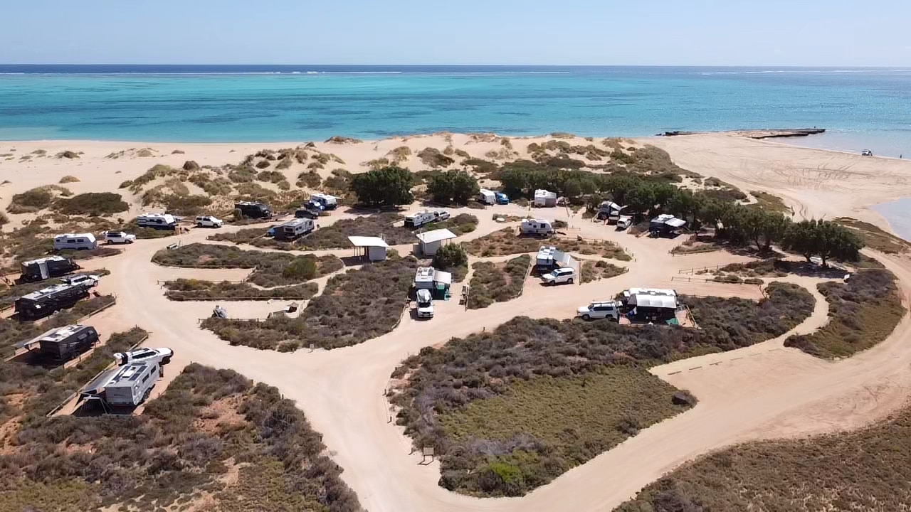 Una vista aérea de vehículos recreativos alrededor del agua azul.