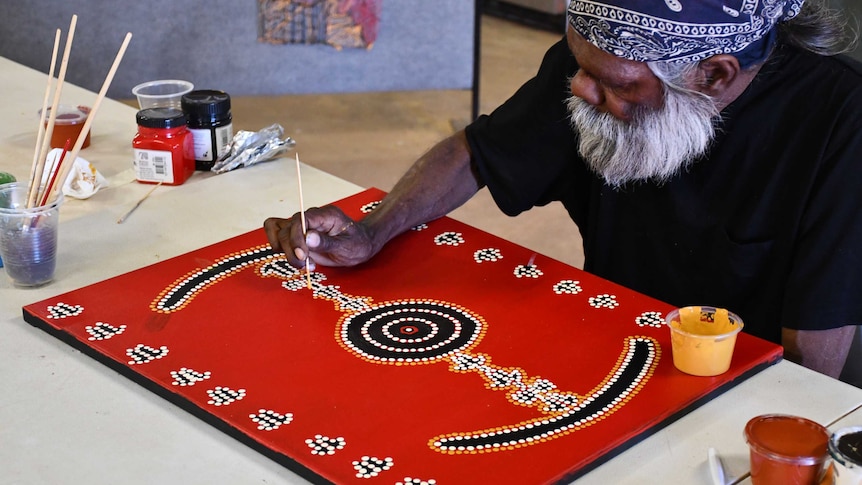 An Aboriginal artist does dot painting.