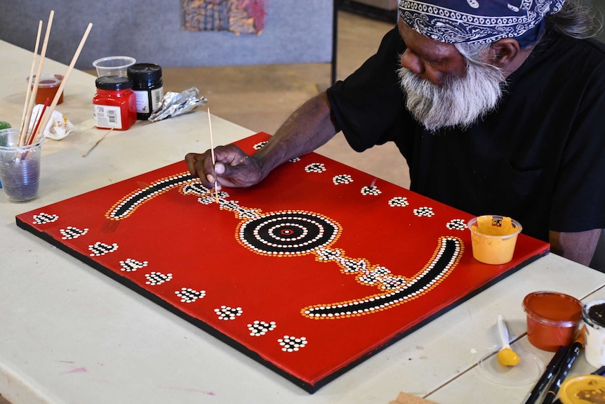 An Aboriginal artist does dot painting.