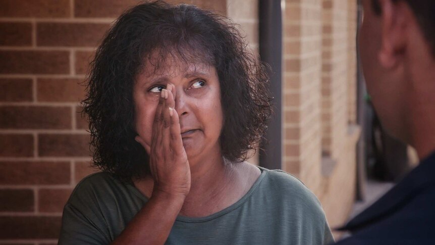 Aboriginal woman Lorna Haines wipes away tears.