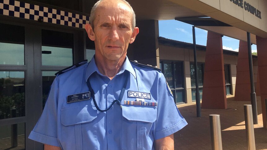 A mid-shot of WA Police Pilbara District Superintendent Paul Coombes posing for a photo in uniform in front of a police station.