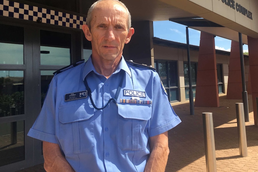 A mid-shot of WA Police Pilbara District Superintendent Paul Coombes posing for a photo in uniform in front of a police station.