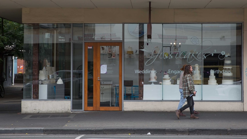 A man and woman walk past the Jessicakes store front