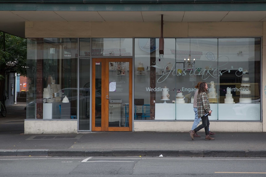 A man and woman walk past the Jessicakes store front