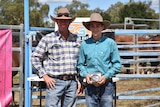 Levi stands next a man with a gold belt buckle in his hand.