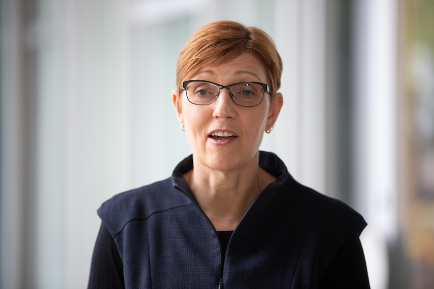 A woman with glasses looks close to the camera.