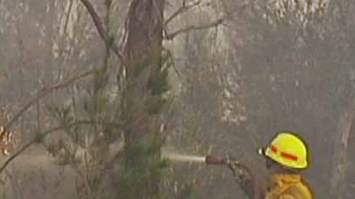 Tasmanian firefighter tries to dampen down flames during the Tasman Peninsula emergency.