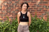 A woman standing in front of a brink wall smiles at the camera