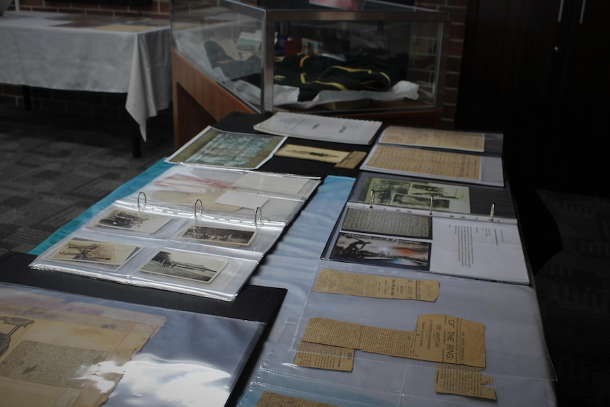 A photo of a table of historical artifacts including newspaper clippings and photographs 