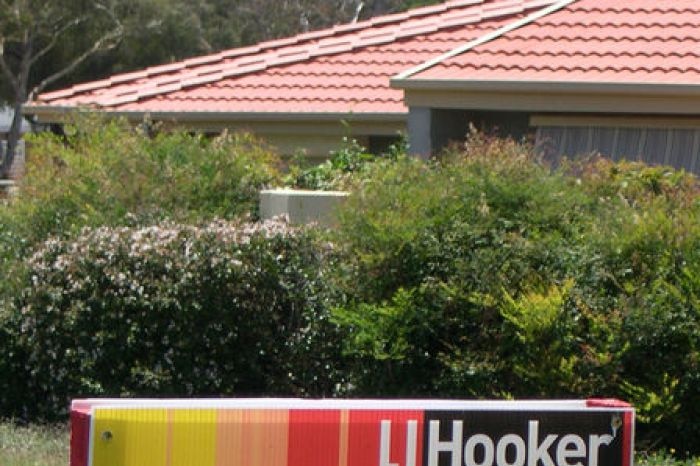 A sign saying for rent stands outside a suburban home.