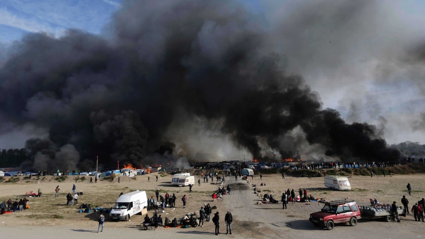 Thick smoke rises from amidst the tents after fires were started in the makeshift migrant camp.