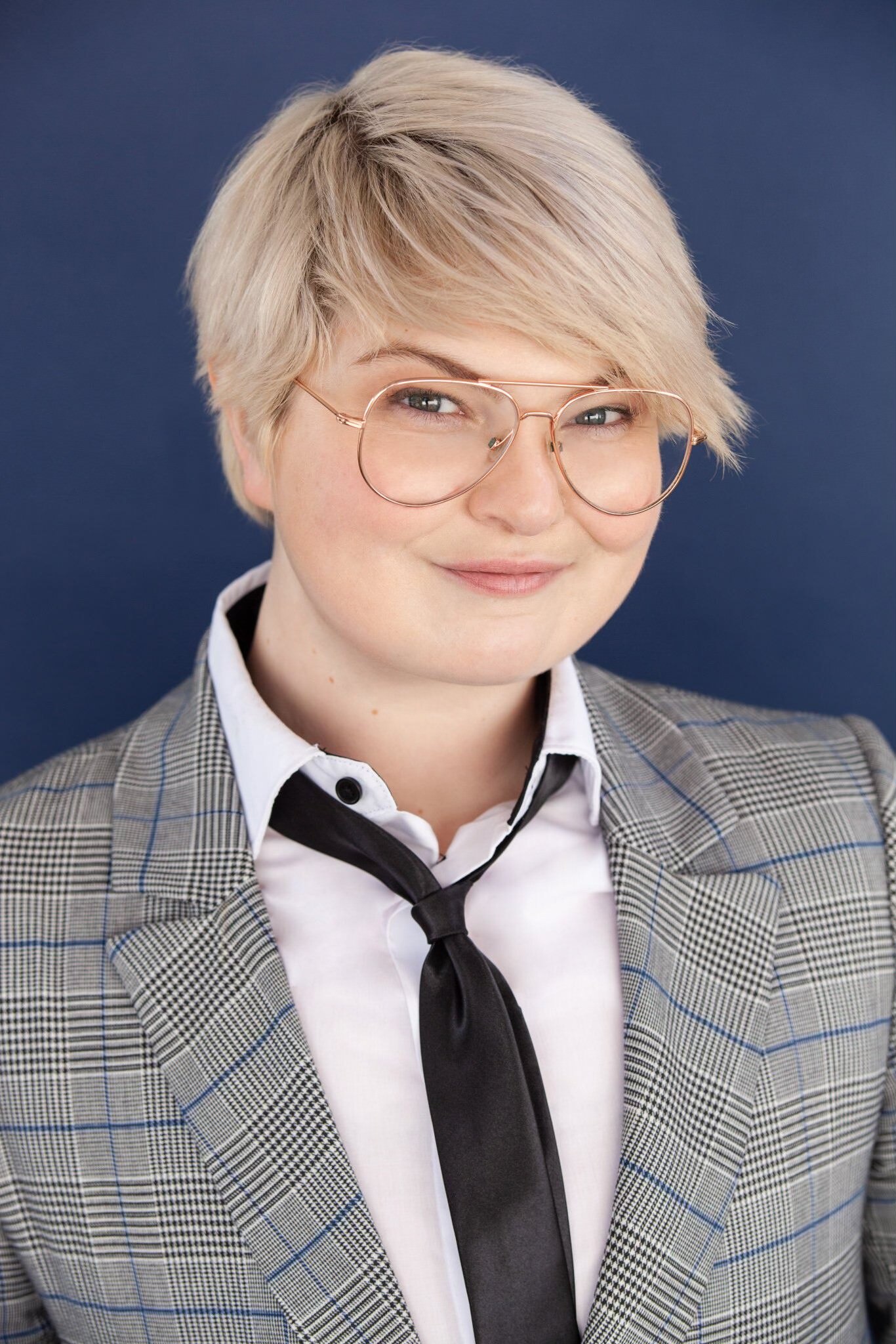 A headshot from a young actor with cropped blonde hair and wire-rimmed glasses