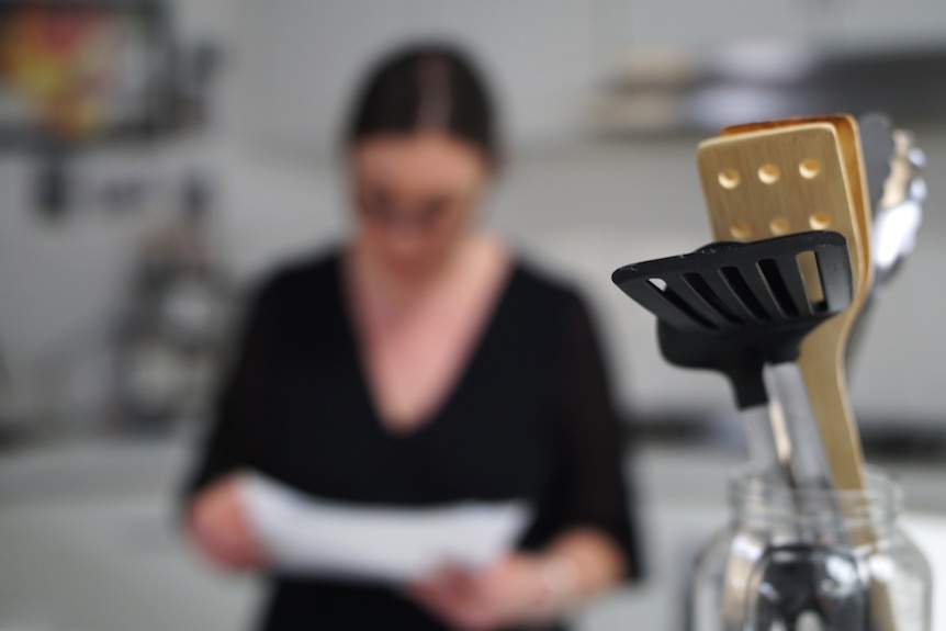 A woman in a black outfit, out of focus, in a kitchen.