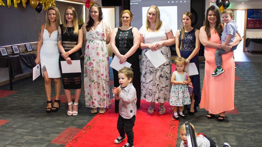 The seven teenage mothers with her certificates, after graduating high school.