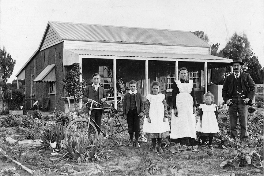 Black and white photo of family pictured outside their rural home.